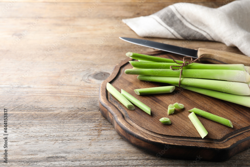 Fresh lemongrass, knife and cutting board on wooden table, space for text Fresh lemongrass, knife and cutting board on wooden table, space for text