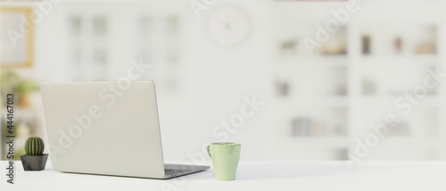 Working table with laptop, mug, copy space and blurred background, 3D render © bongkarn