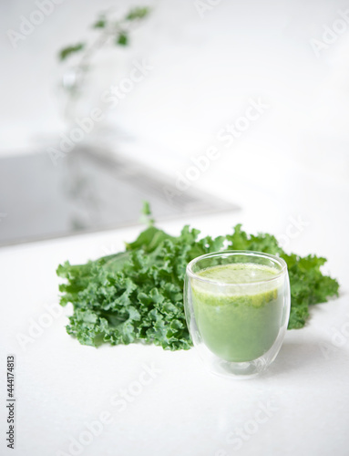 Kale smoothie in glass and kale leaves isolated on mable countertop. Healthy food concept