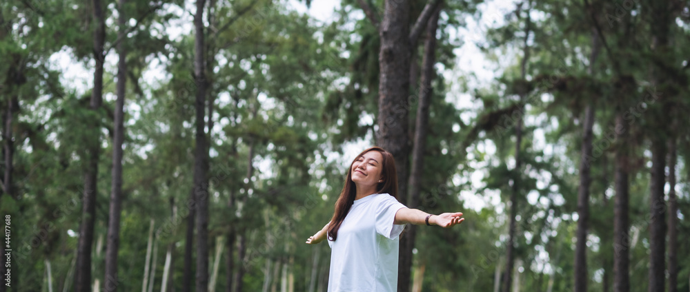 Naklejka premium Portrait image of a happy woman with arms opening in the park