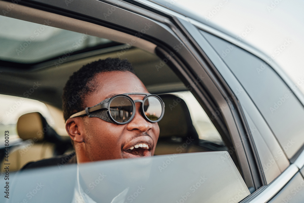 Joyful african businessman with round sunglasses inside of car