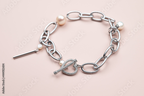 Steel chain bracelet with pearls pendant on pastel pink background