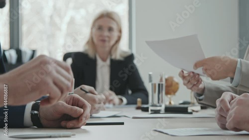 Slowmo PAN midsection shot of unrecognizable businessman giving pile of legal documents to female lawyer or attorney for checking during negotiations with investor photo