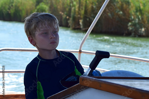 A boy with a concentrated look drives a large motor boat.