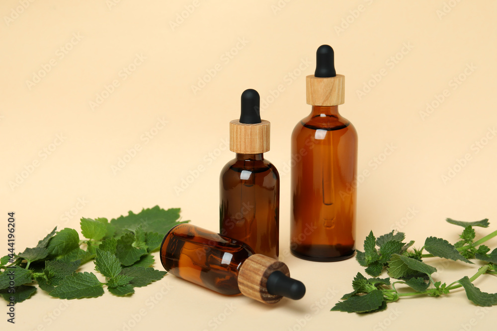 Bottles of nettle essence oil on beige background Bottles of nettle essence oil on beige background