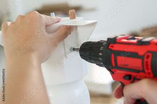 Wallpaper Mural man assembling white table furniture at home using cordless screwdriver Torontodigital.ca