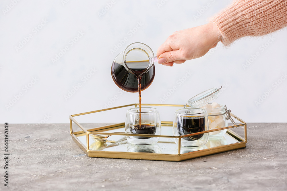 Woman pouring turkish coffee from cezve into cups in kitchen Woman pouring turkish coffee from cezve into cups in kitchen