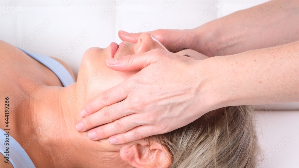 Facial massage beauty treatment. Close up of a young womans face lying on back, getting face lifting massage, pinch and roll technique Facial massage beauty treatment. Close up of a young womans face lying on back, getting face lifting massage, pinch and roll technique