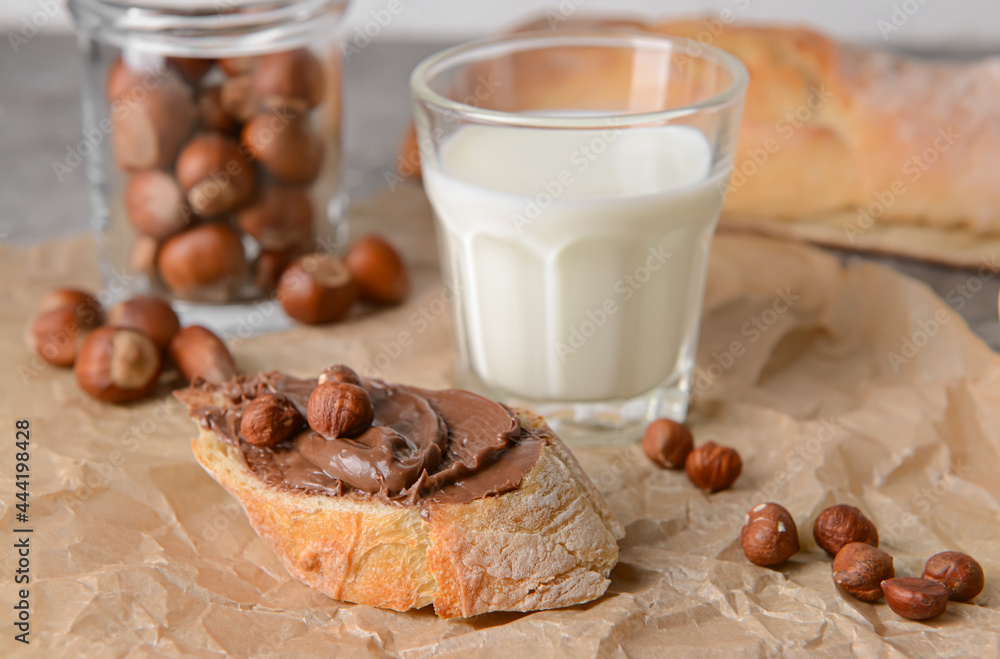 Bowl with tasty chocolate paste and hazelnuts on parchment Bowl with tasty chocolate paste and hazelnuts on parchment