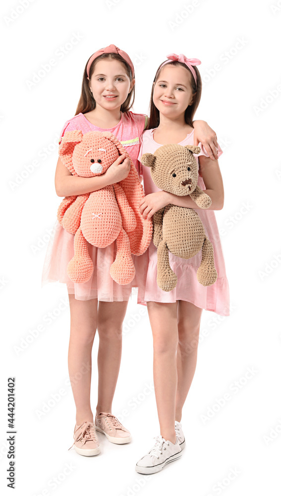 Cute twin girls with toys on white background