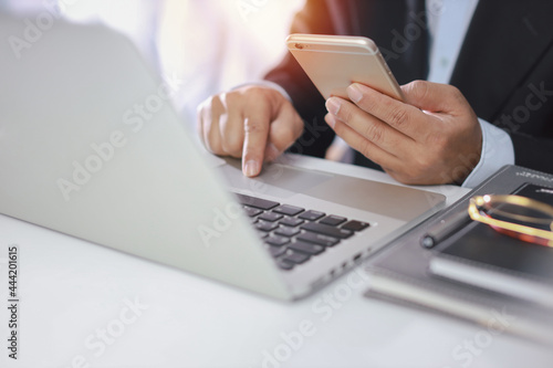 Man hands in black suit sitting and using computer for online payment or shopping online. Business man using mobile phone while working. E-Banking concept