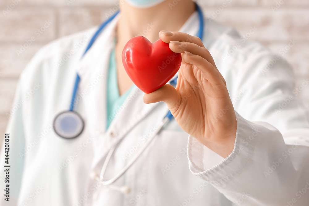 Female cardiologist with red heart near brick wall, closeup Female cardiologist with red heart near brick wall, closeup