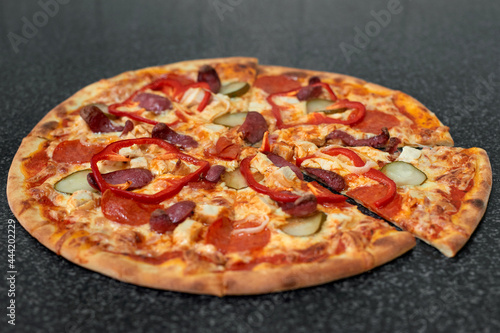 Sliced pizza with sausage, chicken, red pepper, pickles and onions