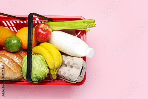 Shopping basket with food on color background photo