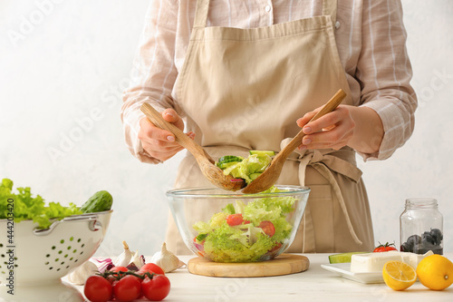 Woman preparing tasty Greek salad in kitchen