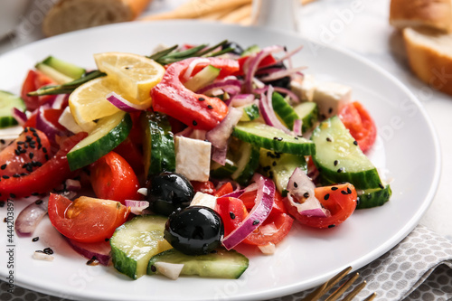 Plate with tasty Greek salad on table, closeup