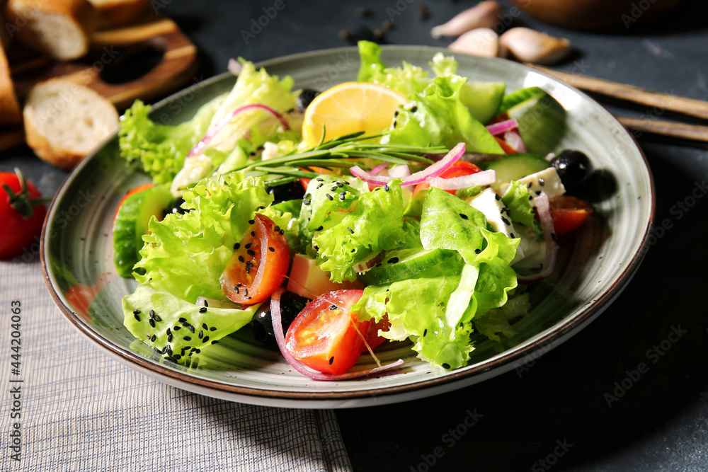 Plate with tasty Greek salad on dark background, closeup