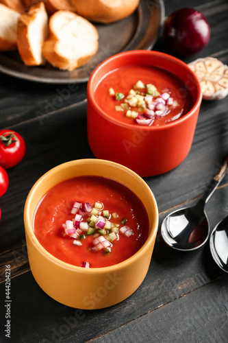 Bowls with tasty gazpacho on dark wooden background