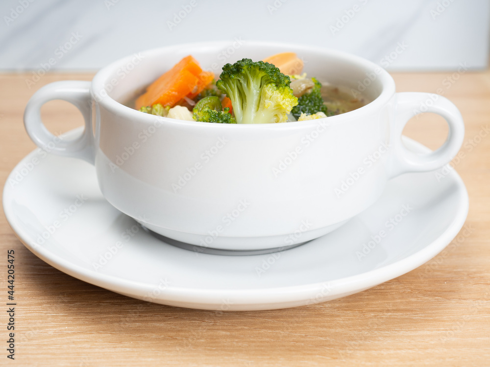 Vegetables soup that contain sausage, broccoli, carrots, etc on a white porcelain bowl Vegetables soup that contain sausage, broccoli, carrots, etc on a white porcelain bowl