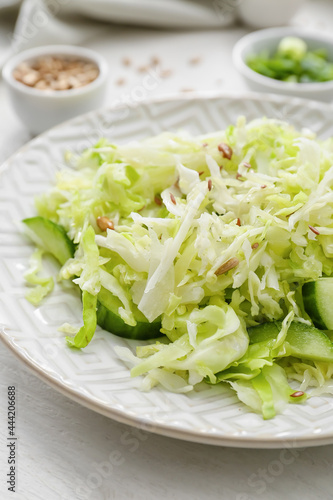Plate with tasty cabbage salad on light wooden table, closeup