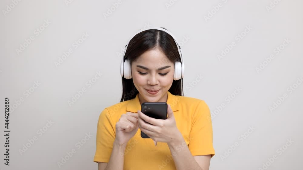 Beautiful young asian women choose song and play music from smartphone connection with wireless headphone having fun in home. Teenage girl listen to the music enjoy relaxing on isolated background. Beautiful young asian women choose song and play music from smartphone connection with wireless headphone having fun in home. Teenage girl listen to the music enjoy relaxing on isolated background.