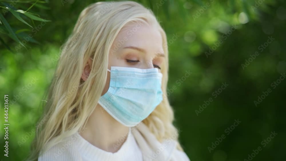 A young woman cannot smell flowers without a mask due to her allergy to the bloom. Living with a spring bloom allergy. Close-up, slow motion, HD. A young woman cannot smell flowers without a mask due to her allergy to the bloom. Living with a spring bloom allergy. Close-up, slow motion, HD.