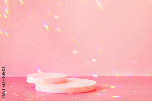 Abstract minimal scene - empty stage, two cylinder podiums on pink background with rainbow crystal light refraction sparkles. Pedestal for cosmetic product and packaging mockups display presentation