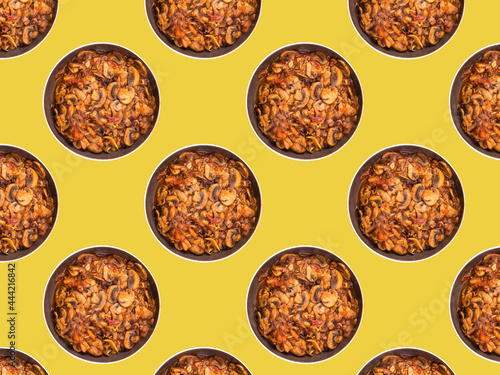 Kitchen food pattern, flat lay - fried mushrooms with tomatoes in bowls on a yellow background, vergetarian pattern photo