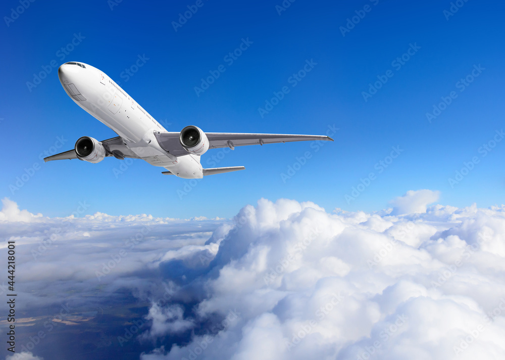 Airplane flying above clouds on blue sky background