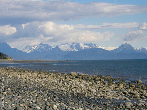 looking out at the snow-capped glaciated peaks of the katmai peninsula across kachemak bay in summer  from the rocky  beach  at homer, alaska photo