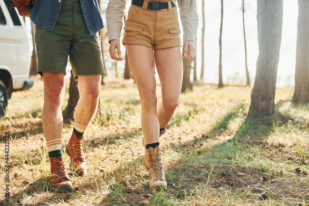 Walking on grass. Young couple is traveling in the forest at daytime together