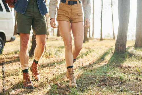 Walking on grass. Young couple is traveling in the forest at daytime together