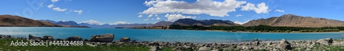 panorama of the spectacular turquoise- colored water of  lake tekapo on a sunny summer day against a mountain backdrop of the southern alps, on the south island of new zealand photo