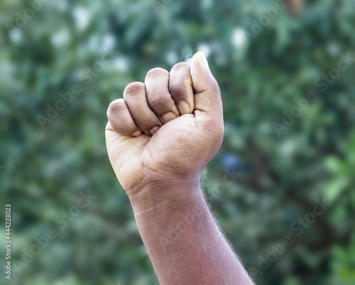Men strong fist hand stretching up on soft green bokeh background © Xookits