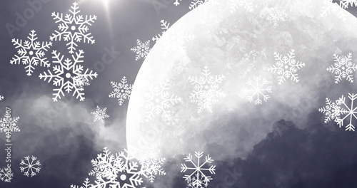Snow particles falling against moon in night sky