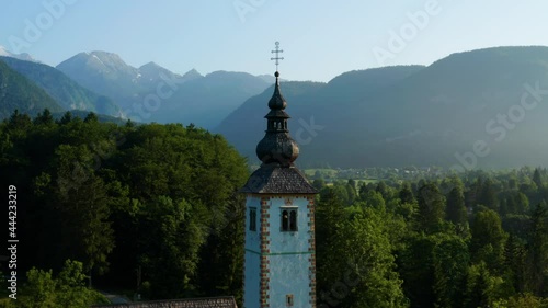 Close Up Of The Tower Of Church Of St. John The Baptist In Bohinj, Slovenia With Mountains And Trees In Background. photo
