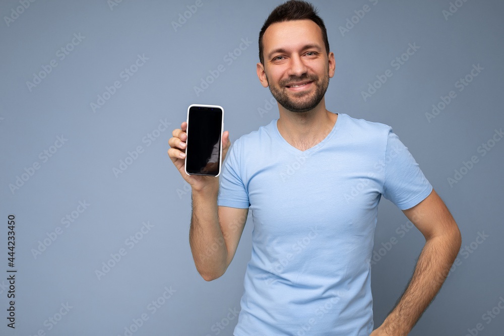 Handsome happy cool young man good looking wearing casual stylish clothes standing isolated over colourful background wall holding smartphone and showing phone with empty screen display looking at Handsome happy cool young man good looking wearing casual stylish clothes standing isolated over colourful background wall holding smartphone and showing phone with empty screen display looking at