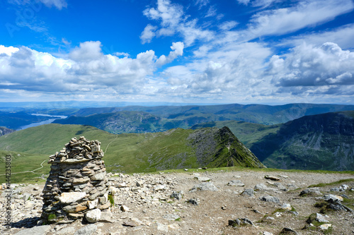 Looking down Striding Edge towards Ullswater and Glenridding from the summit of Helvellyn in the Lake District. Shot in landscape with a stone cairn in the foreground © Jenny
