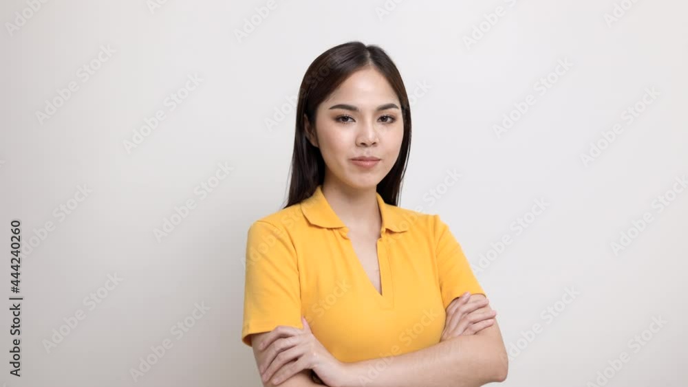 Beautiful young asian woman in yellow shirt smiling and happy. Charming female standing with arms crossed on isolated white background. Beautiful young asian woman in yellow shirt smiling and happy. Charming female standing with arms crossed on isolated white background.