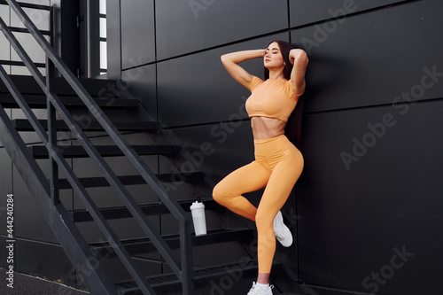 On stairs with bottle of water. Young woman in sportswear have fitness session outdoors