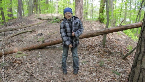the boy in the forest smiles,a boy puts a clasp in his jacket in the woods photo