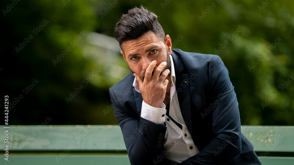 Conversational young man outdoors sitting outside on a bench in the park nature Conversational young man outdoors sitting outside on a bench in the park nature