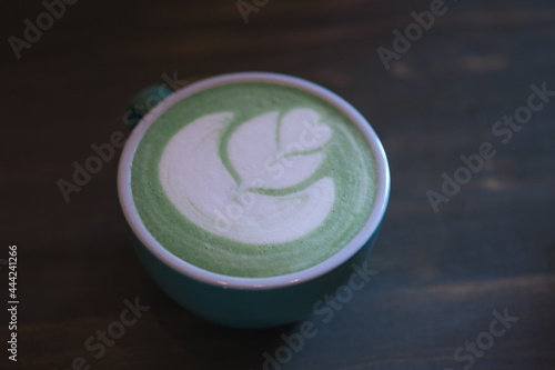 A cup of green matcha latte tea on the table, latte art