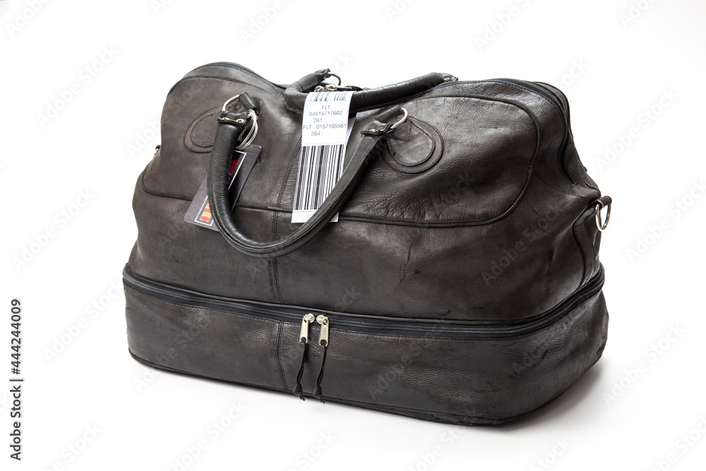Naklejka premium A black leather, suitcase, travel bag with a faux airline baggage check tag.