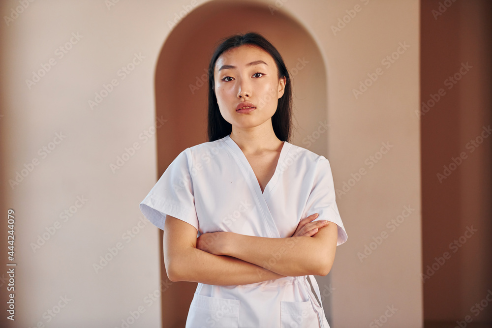 Young female doctor in white coat standing indoors Young female doctor in white coat standing indoors