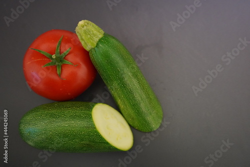 Fresh vegetables from the garden for a delicious dinner recipe. Beautiful bright red tomato and a green zucchini. 