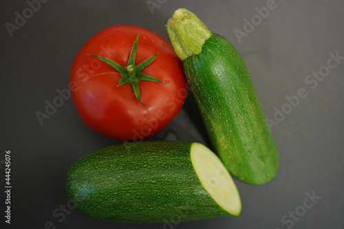 Fresh vegetables from the garden for a delicious dinner recipe. Beautiful bright red tomato and a green zucchini. 