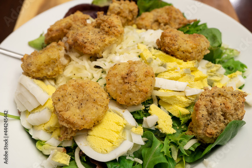 Fried shrimp, made using an air fryer, atop a bed of spinach, mixed greens, hard boiled eggs, and Mozzarella cheese