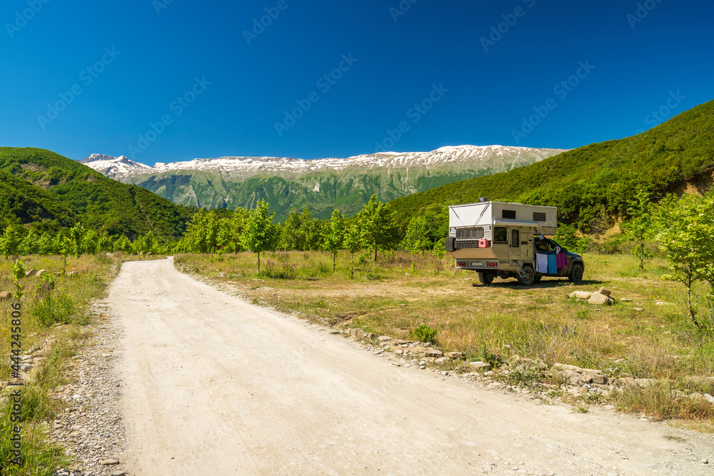 Small travel vehicle camping van is parked under huge mountain formation. Tourism vacation and travel. Camper van and mountains landscape Small travel vehicle camping van is parked under huge mountain formation. Tourism vacation and travel. Camper van and mountains landscape