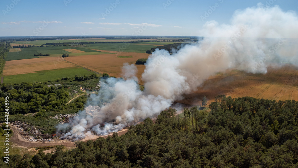 Fototapeta premium Burning rubbish dump. City dump on fire. Concept of ecological problem
